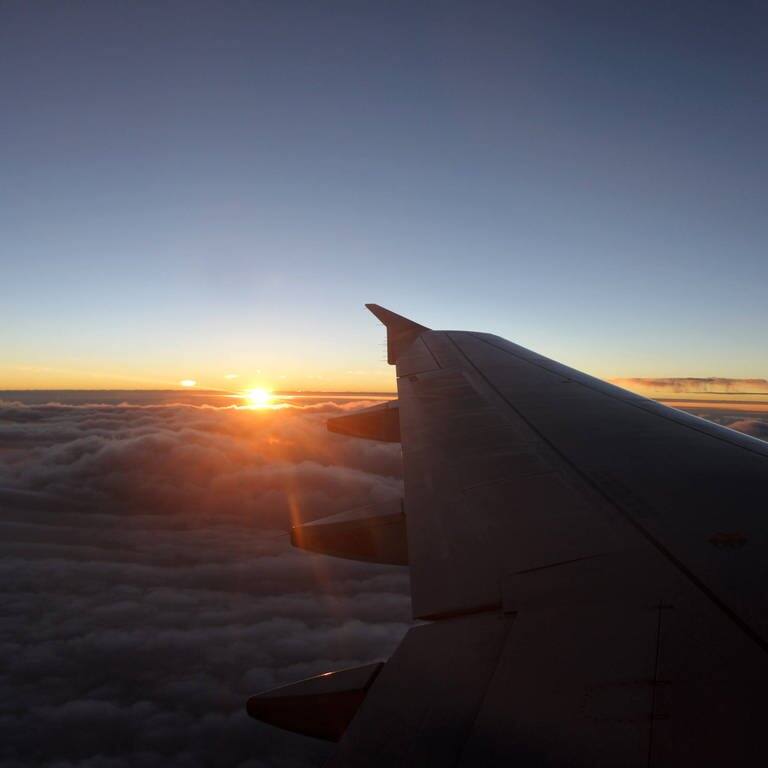 Sonnenuntergang aus dem Flugzeug-Fenster - klimaneutrales Reisen (Foto: IMAGO, IMAGO / Newscom World)